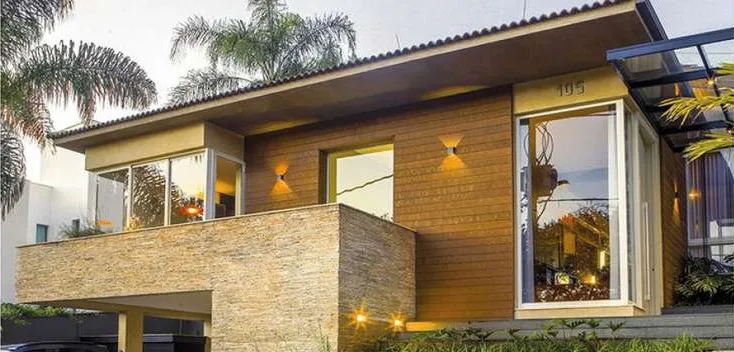 Fachada residencial revestida com madeira ecológica e iluminação noturna
